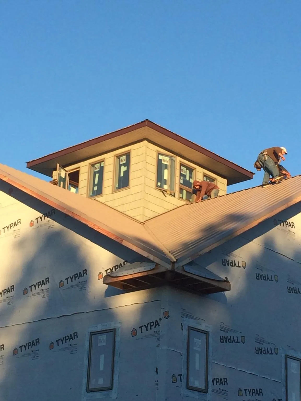 Roofers working around a rooftop cupola on a new metal roof at sunset — Roof Waterproofing in Kingwood by Roofing Brothers